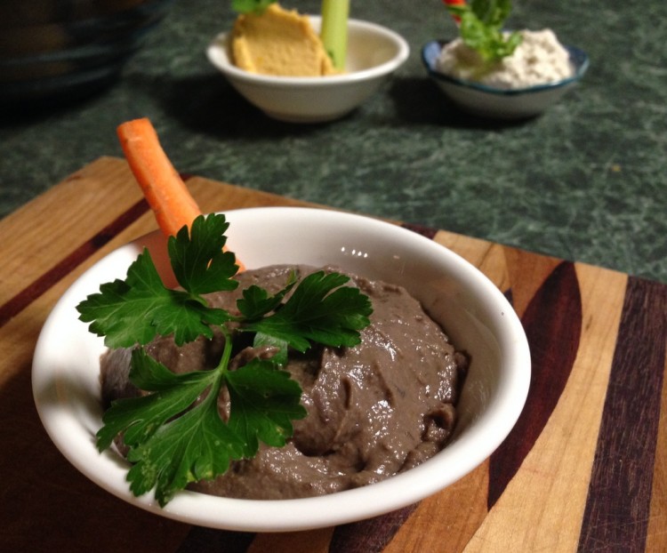 Plate with baba ganouj with garnish of parsley and a stick of carrot